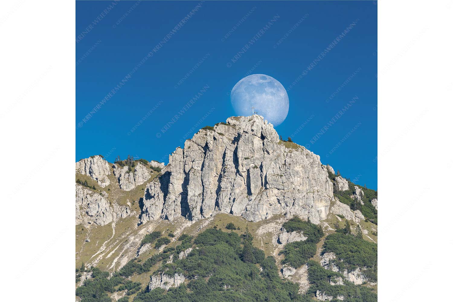 Aufgehender Vollmond hinter Signalkopf mit Wanderer am Gipfel