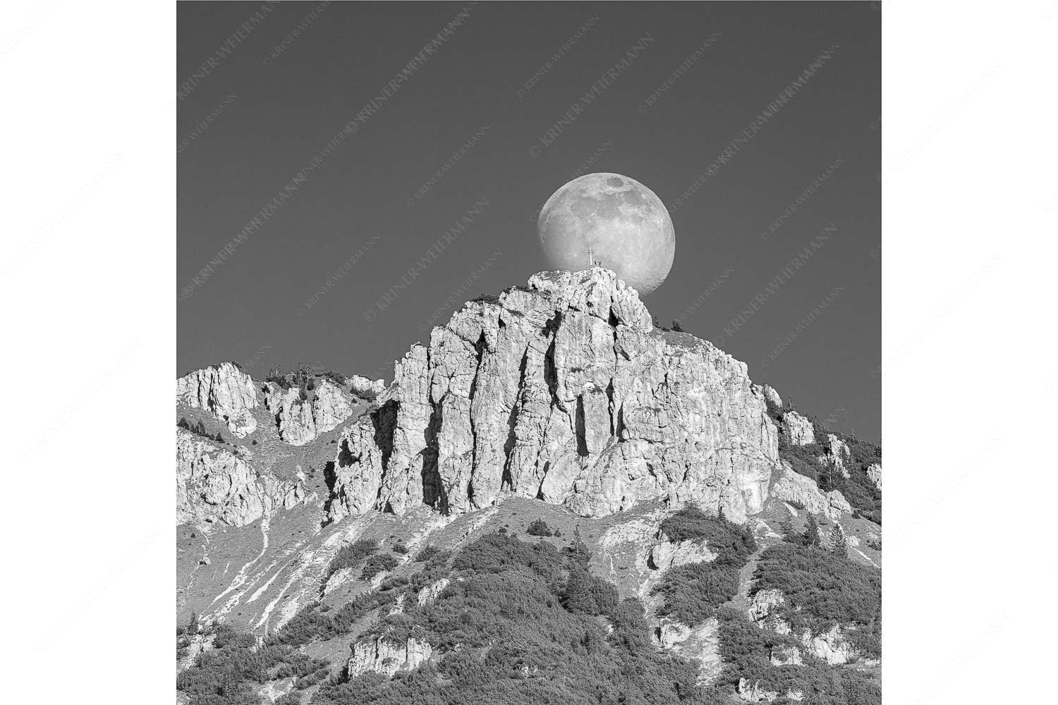 Aufgehender Vollmond hinter Signalkopf mit Wanderer am Gipfel