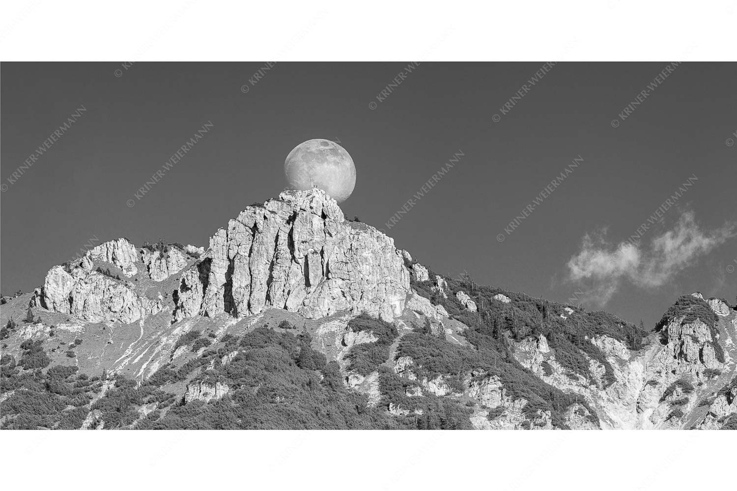 Aufgehender Vollmond hinter Signalkopf mit Wanderer am Gipfel
