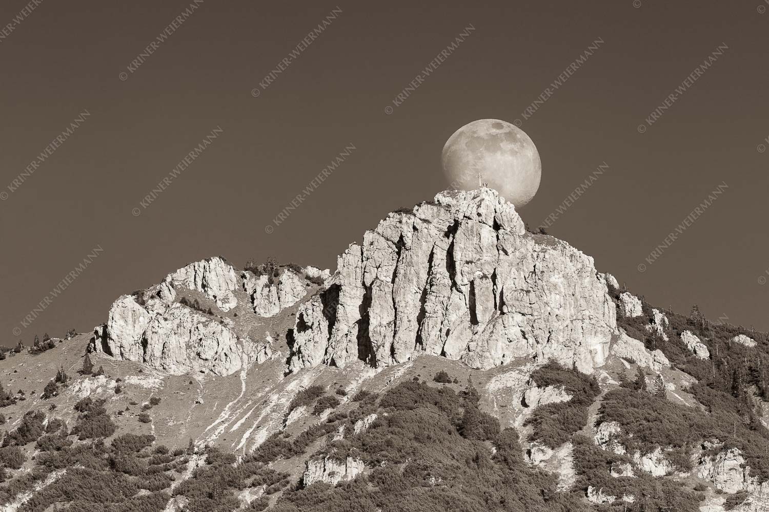 Aufgehender Vollmond hinter Signalkopf mit Wanderer am Gipfel