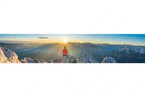 Blick übers Obere Isartal in den Sonnenaufgang im Karwendel - Sonnenanbeter - Seitenverhältnis 5:1 - Bergsteiger auf der Wettersteinspitze - weitere Infos unter https://www.kriner-weiermann.de